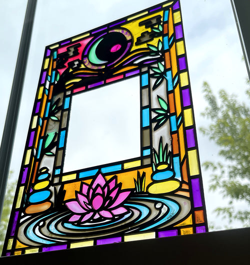 Lotus and moon stained glass style suncatcher panel hanging in a window, pink lotus on rippling water, crescent moon and cloud above, green bamboo down both sides